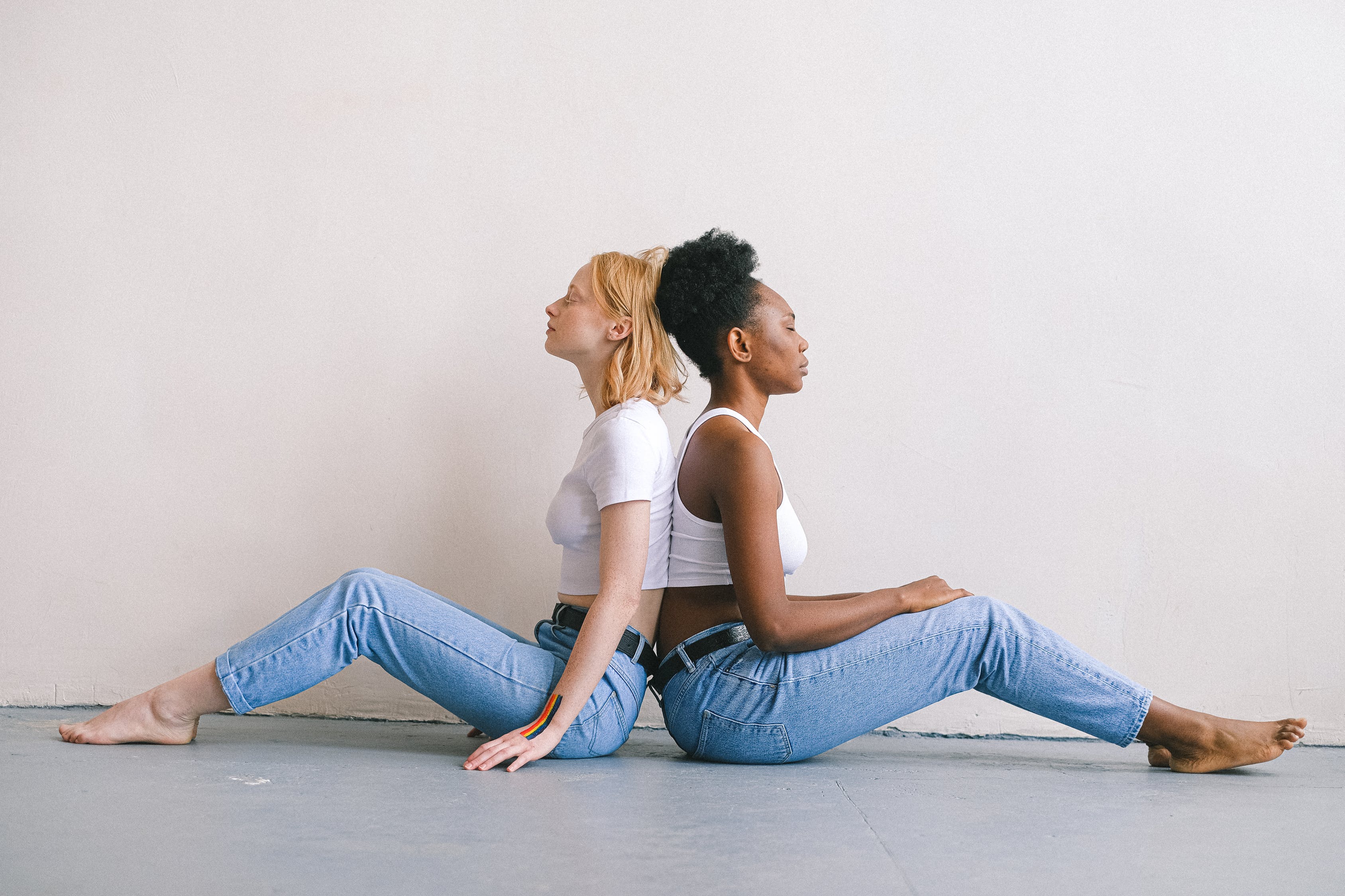 Women back to back sitting on the floor